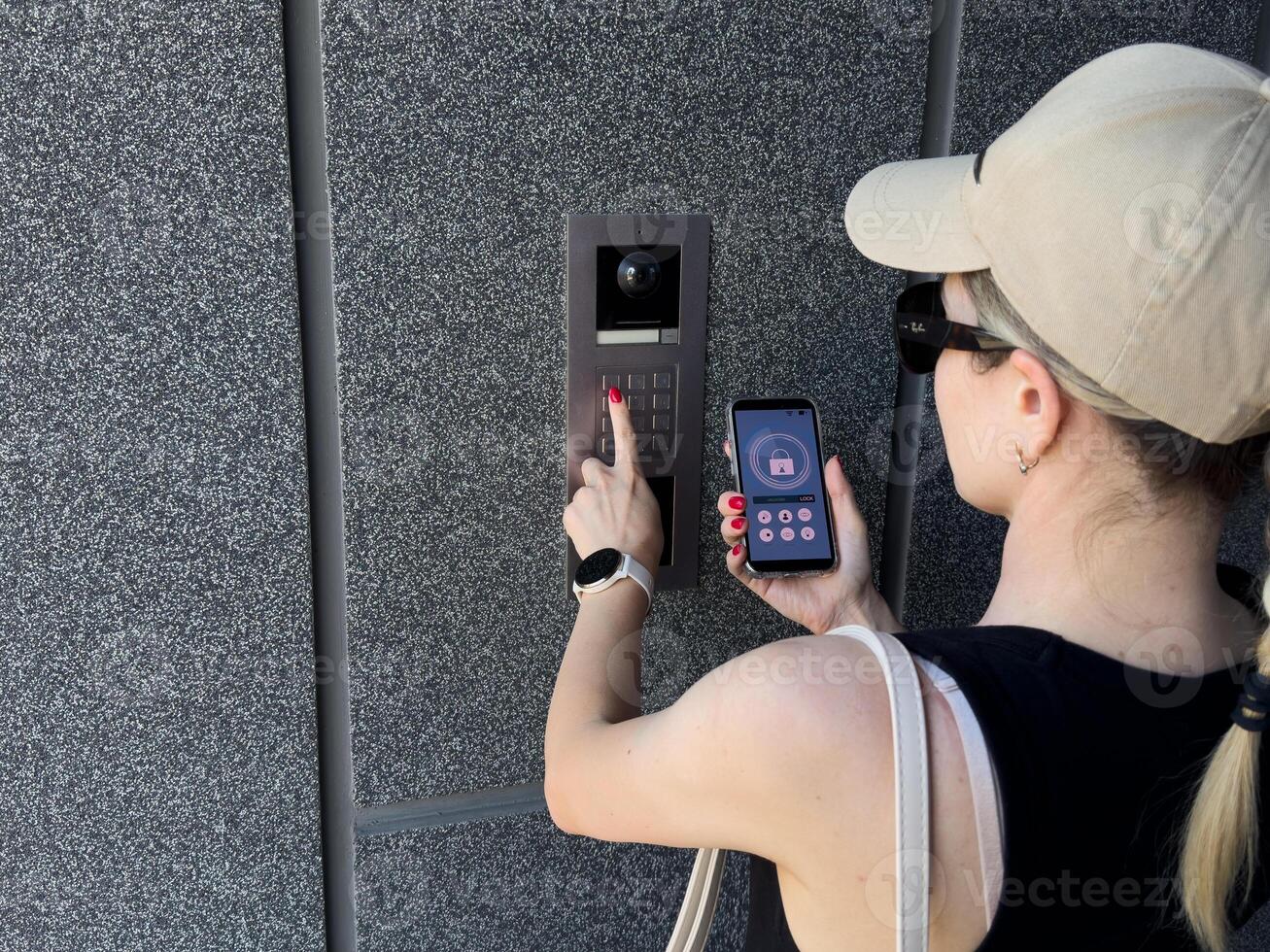 Close up of woman using intercom at building entrance. photo