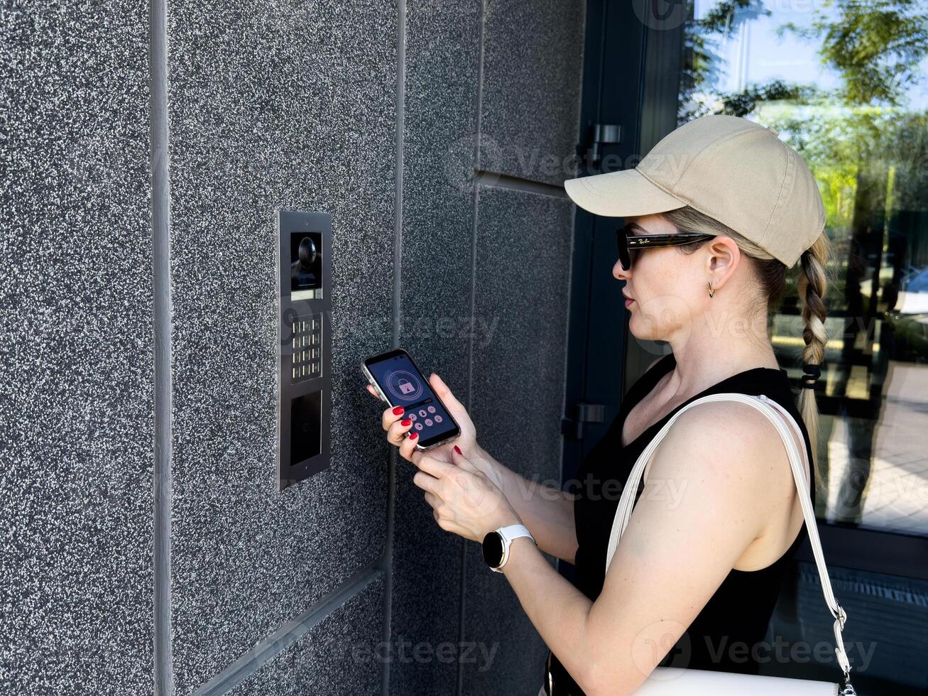 Close up of woman using intercom at building entrance. photo