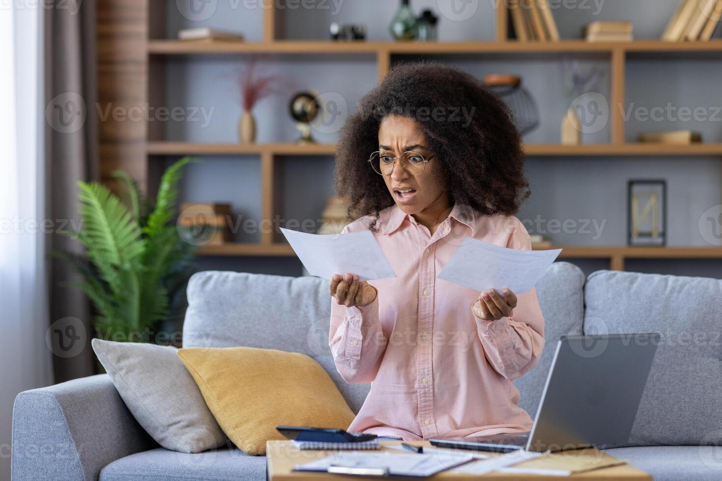 Upset and distressed woman working with documents and papers at home, paying utility bills and loan payments, shocked by high interest rates for insurance and mortgage. photo