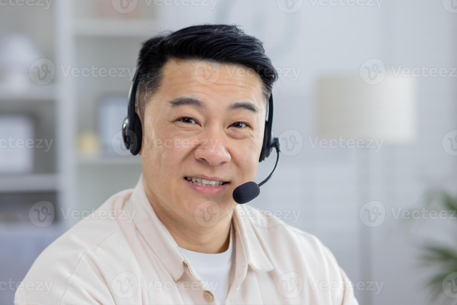 Portrait of a happy middle-aged Asian man wearing a headset, working remotely from his home office. He shows a friendly and professional attitude. photo