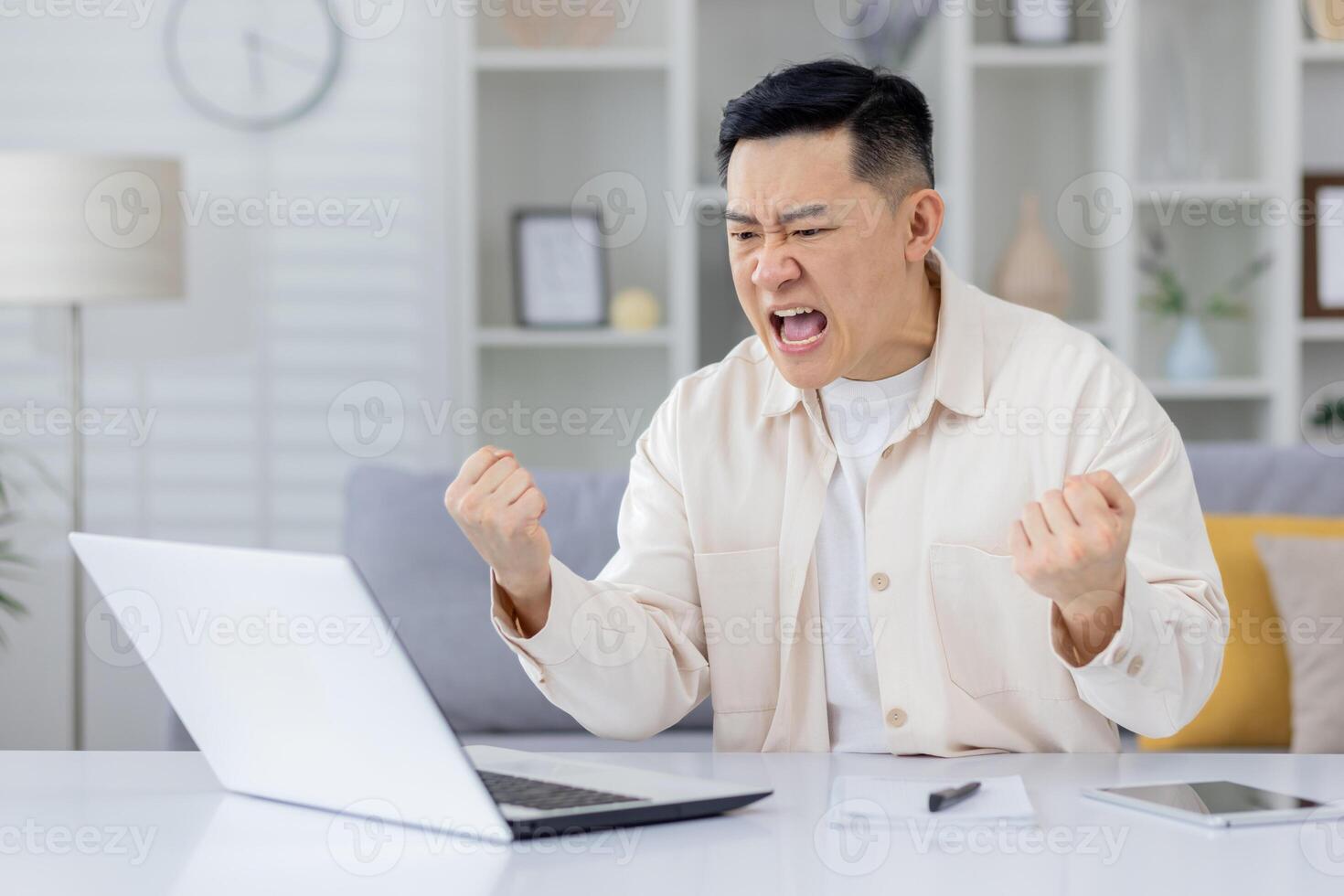 An adult man expressing frustration and anger while working from home, upset with laptop screen. This image captures an intense moment of emotional stress in a remote work environment. photo