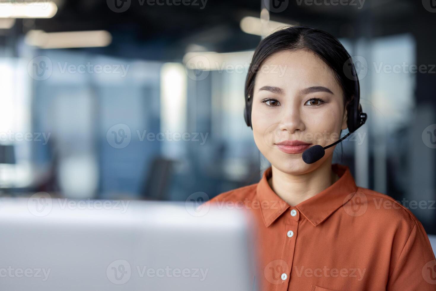 Asian businesswoman wearing a headset, working in a modern office environment with a friendly and professional demeanor. photo