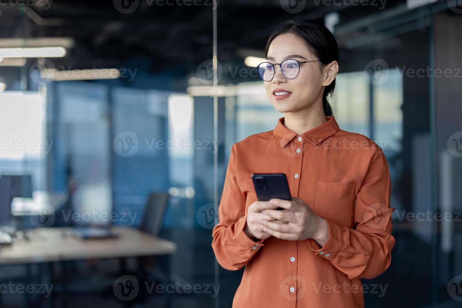 Asian businesswoman using smartphone in modern office. Captures professional confidence and workplace environment. Ideal for business, technology, and communication concepts. photo