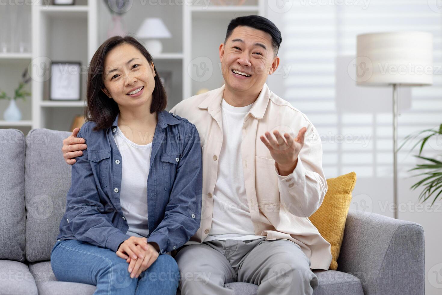 Joyful couple sitting on a cozy sofa at home, smiling and enjoying their time together. Perfect image for family, relationships, and happiness concepts. photo