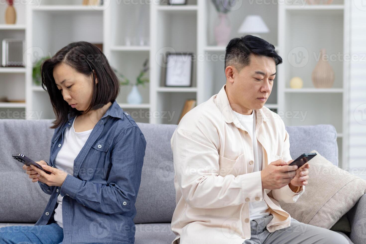 Couple sitting apart on a sofa, focusing on their smartphones. Concept of technology affecting relationships and communication. photo