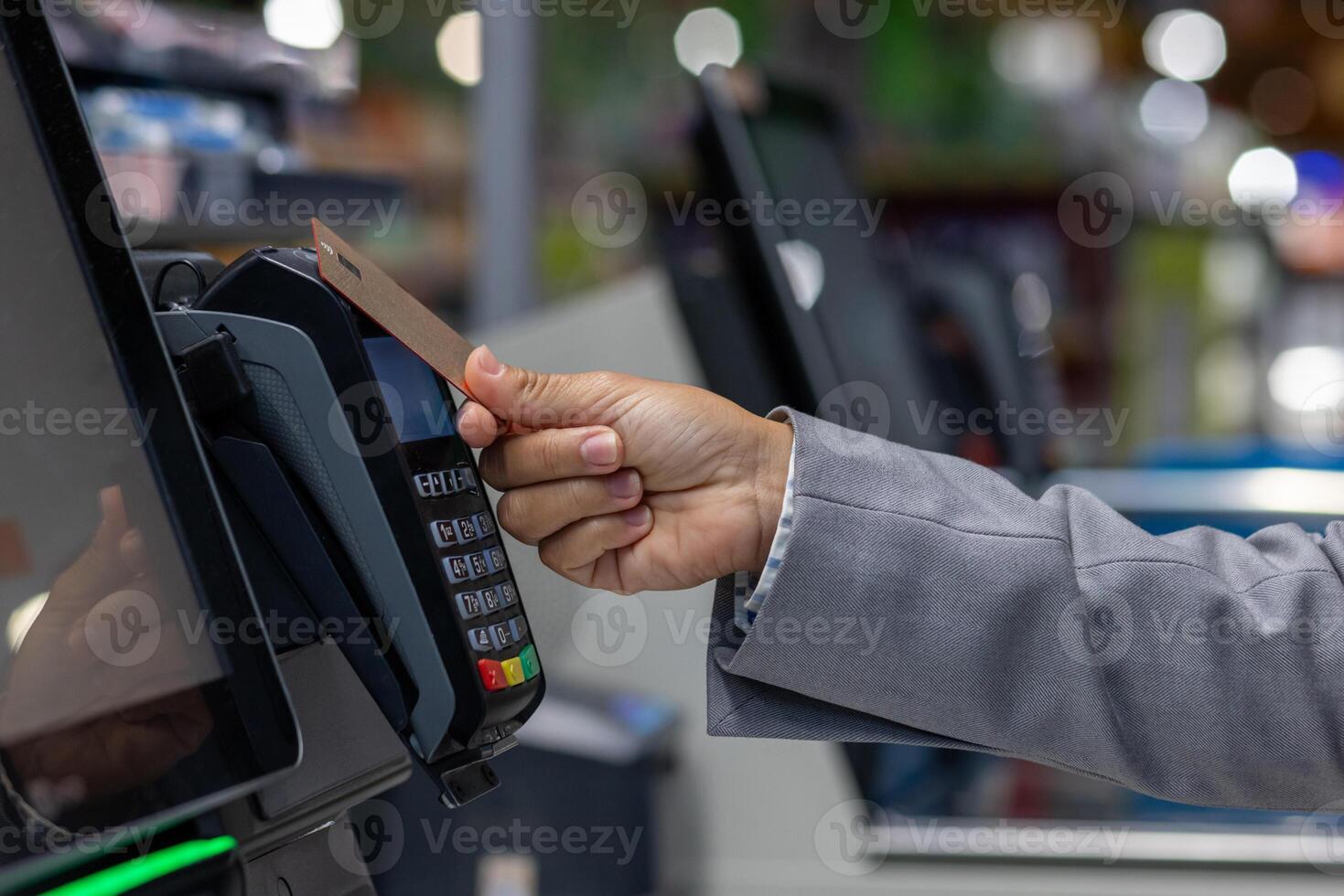 Close-up photo of the hand of a female buyer paying in a supermarket store with a bank credit card at the self-service checkout