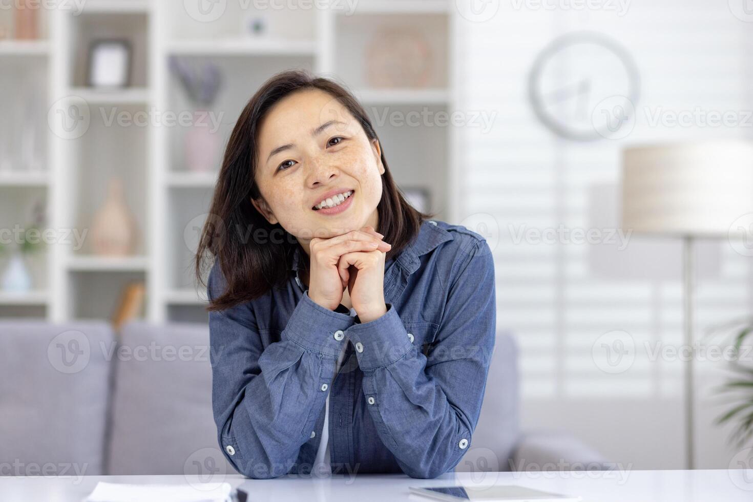 Friendly woman smiling while sitting at a desk in a modern home office setting. She looks relaxed and approachable. photo