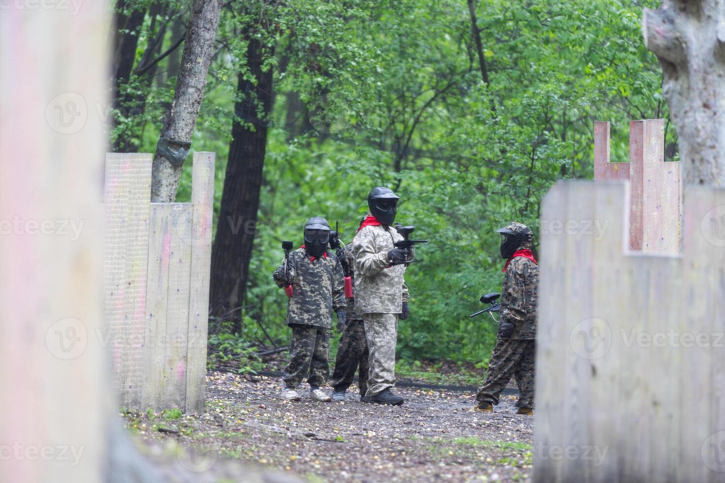 Warriors in camouflage and masks playing paintball photo