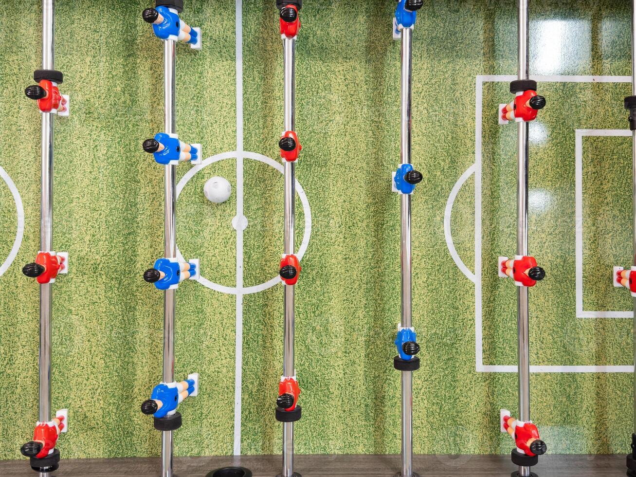 Classic Foosball Table Game With Players in Red and Blue Jerseys During Daytime Indoor Match. Close-up view of foosball table featuring red and blue jersey players positioned for daytime indoor game. photo