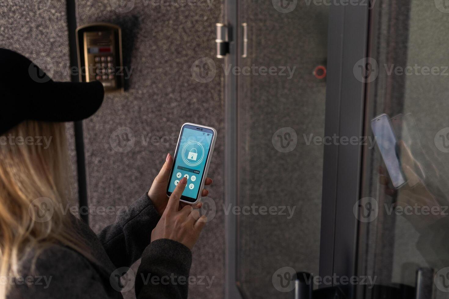 Woman locking smartlock on the entrance door using a smart phone. Concept of using smart electronic locks with keyless access. photo
