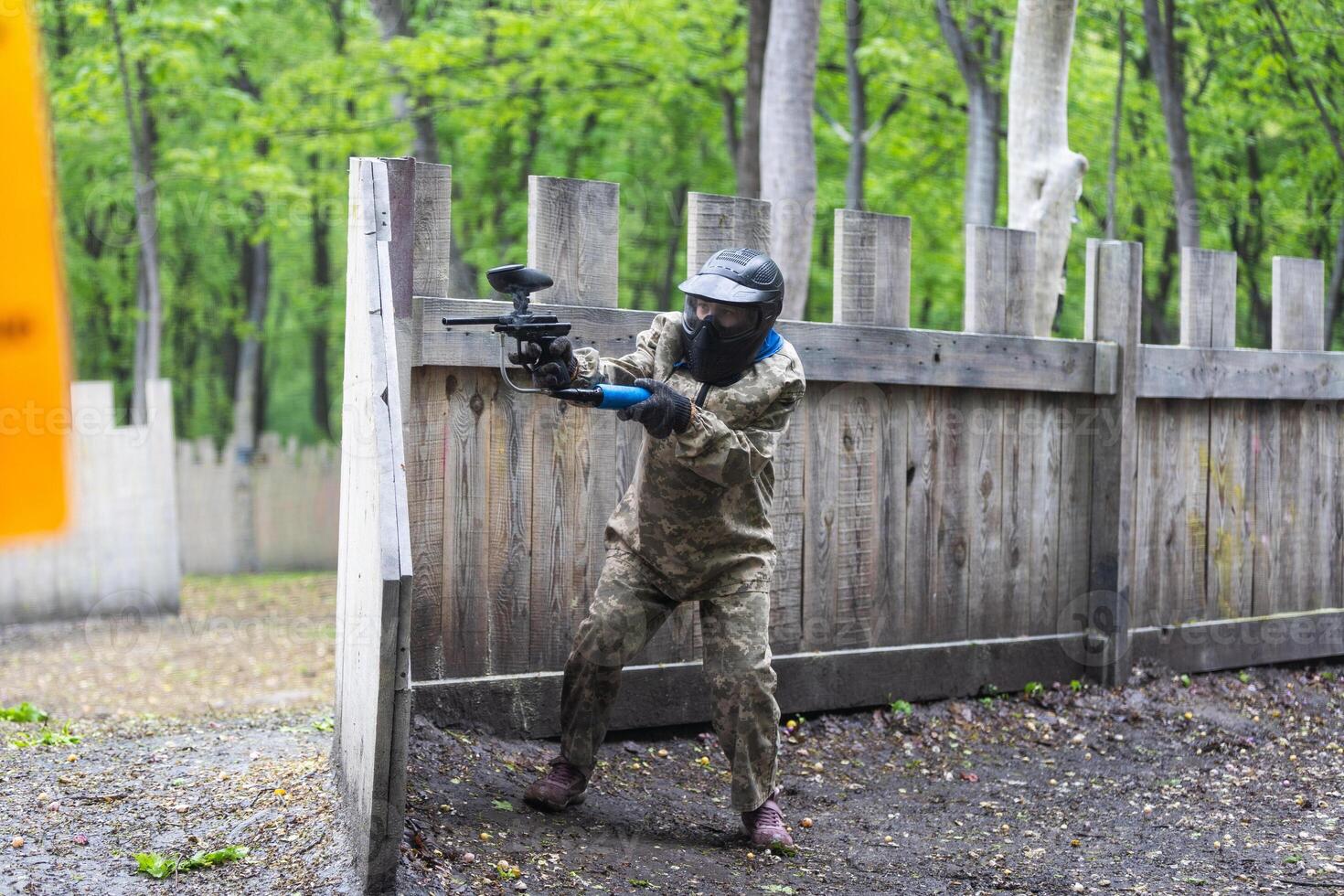 Paintball game. Players with weapons shooting paint balls. Men on the playground. Guys in camouflage and masks are fighting. photo