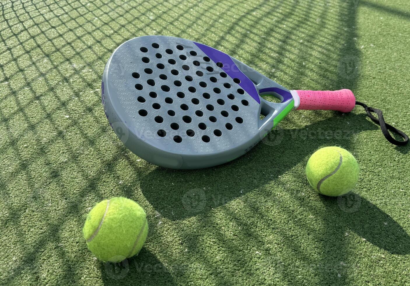 Paddle tennis racket, ball and net on the grass photo