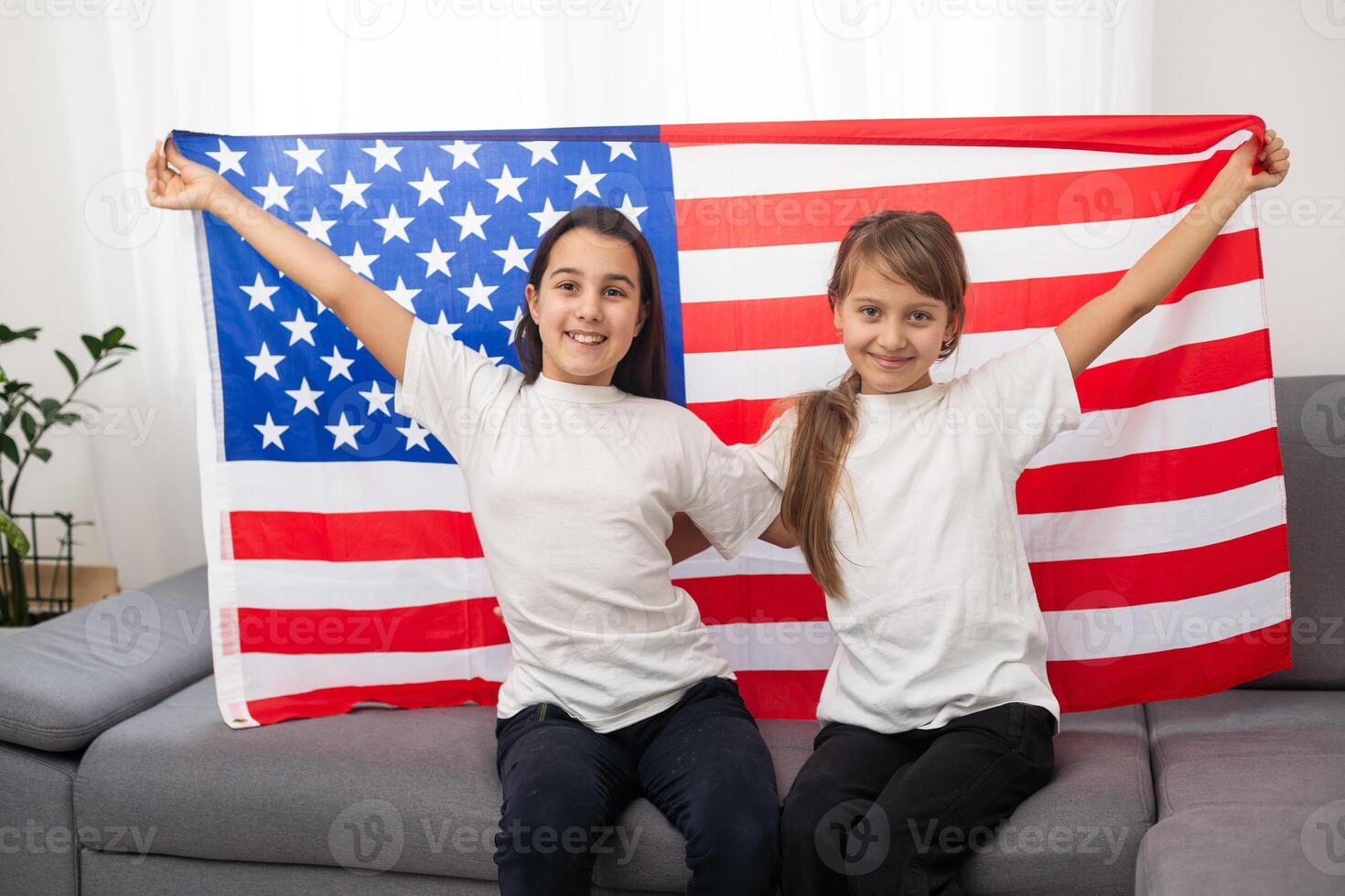 cheerful adorable kids standing under american flag and looking at camera photo