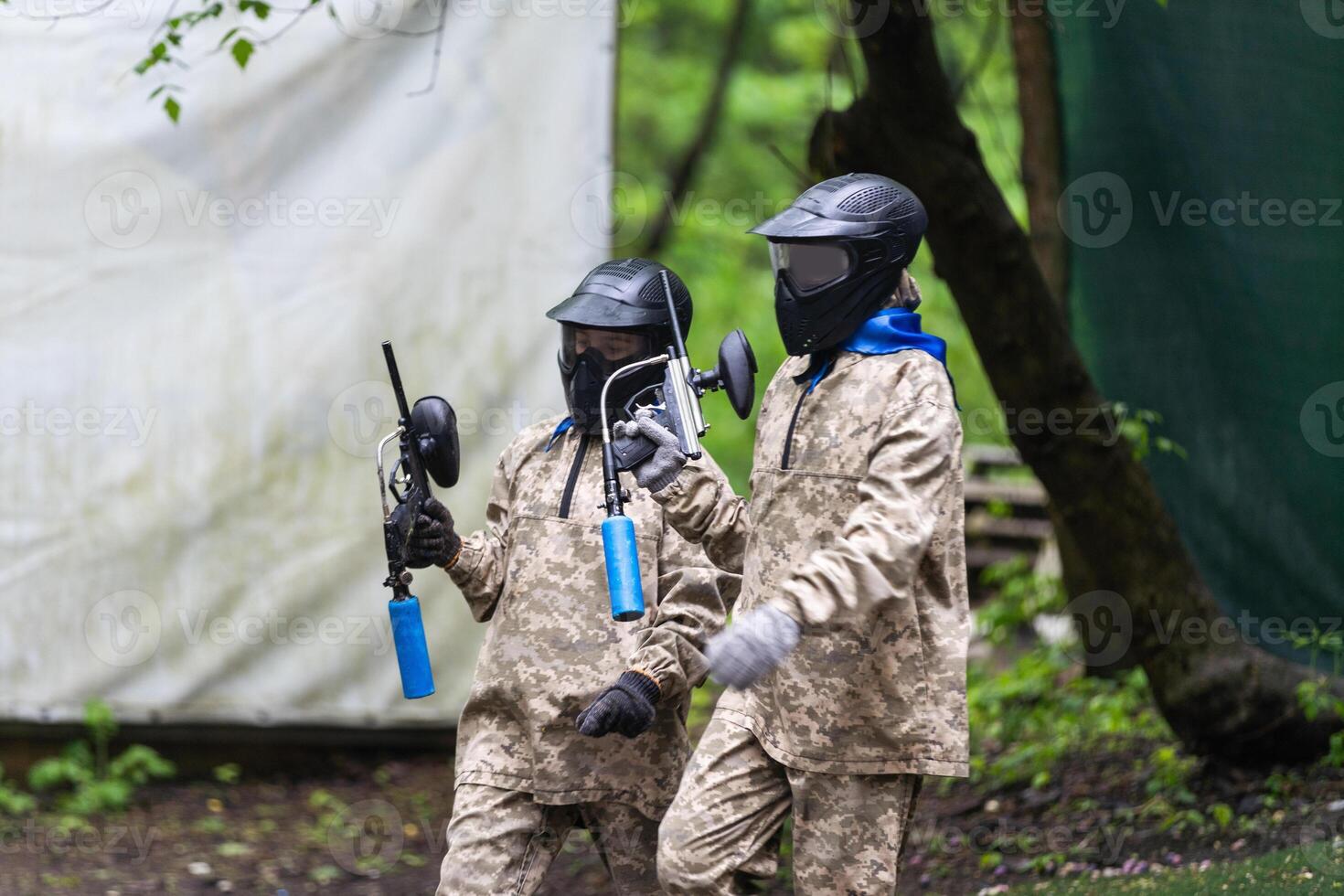 Warriors in camouflage and masks playing paintball photo