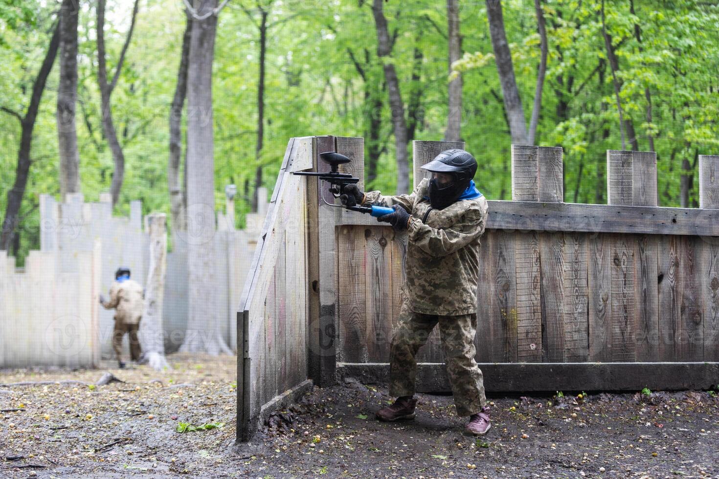 Warriors in camouflage and masks playing paintball photo