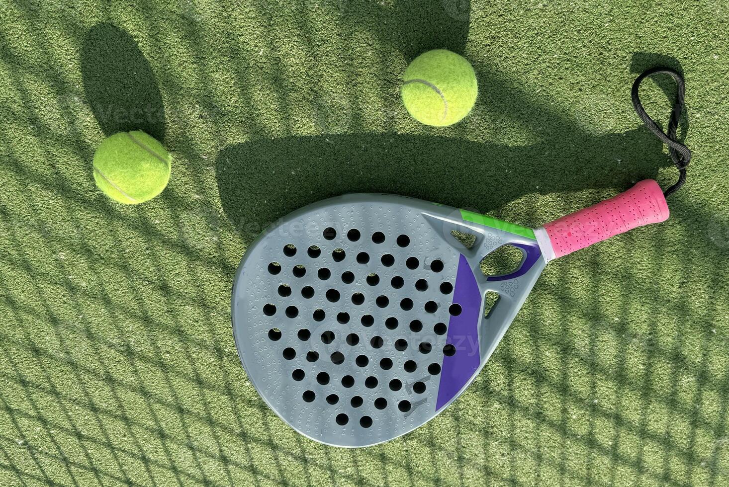 Paddle racket with a ball ready to play the fastest growing sport in recent years worldwide. Padel court in summer, the perfect time to practice this sporting discipline and release stress. photo