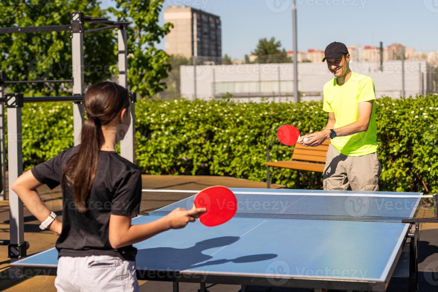 Happy man with his daughter playing ping pong in park photo