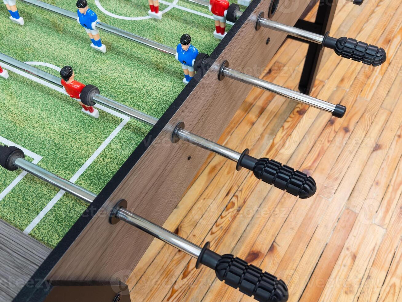 Classic Foosball Table Game With Players in Red and Blue Jerseys During Daytime Indoor Match. Close-up view of foosball table featuring red and blue jersey players positioned for daytime indoor game. photo