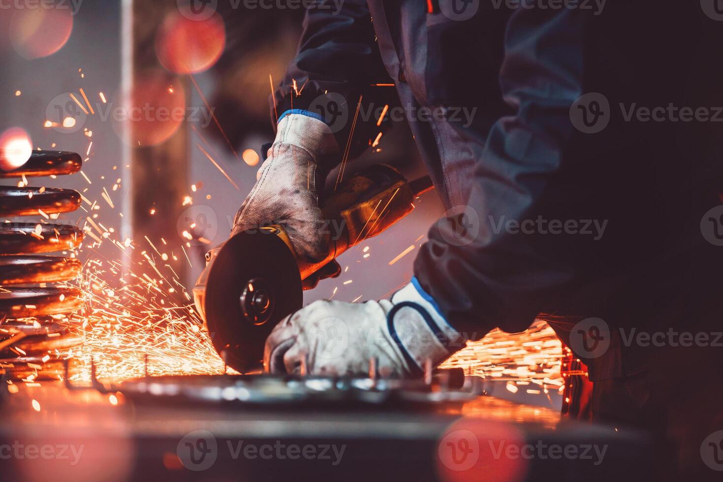 Locksmith in special clothes and goggles works in production. Metal processing with angle grinder. Sparks in metalworking. photo