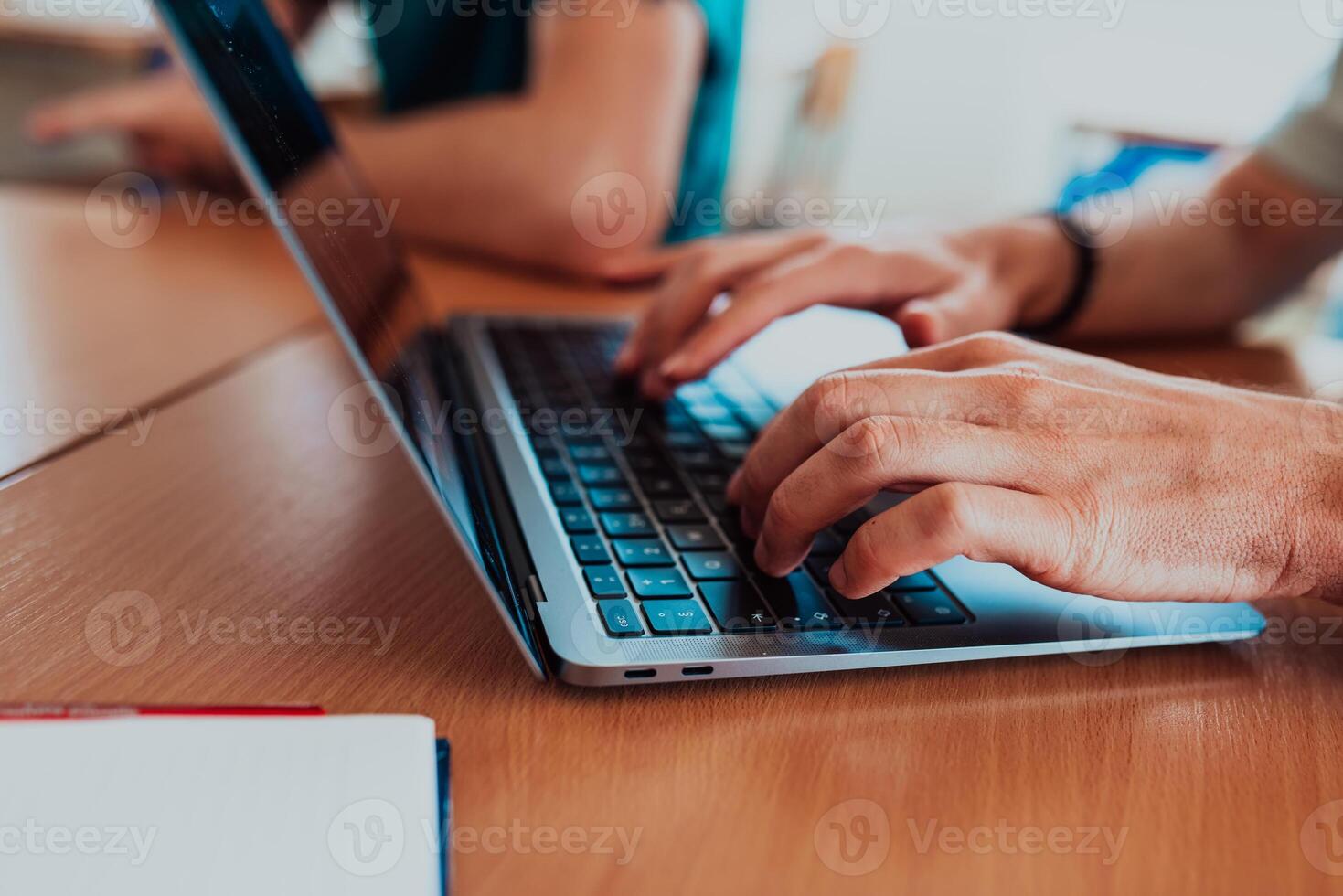 In a close-up view, the fingers of a man are seen typing swiftly on a laptop keyboard, depicting a scene of focused productivity in a digital work environment photo