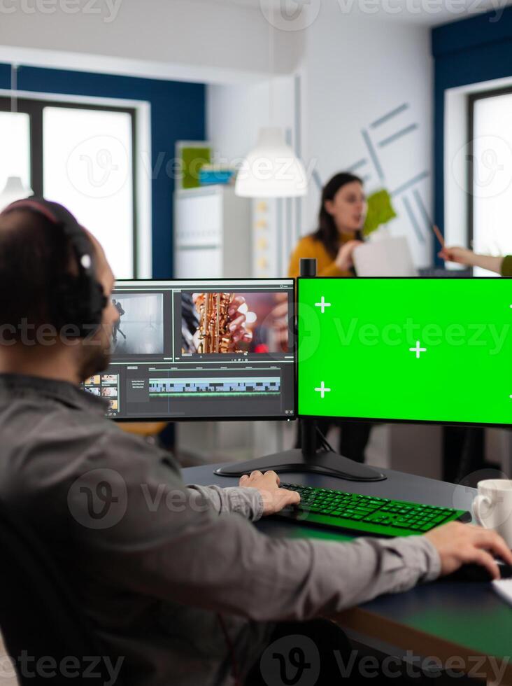 editor processing movie montage cutting footage at pc with green screen, chroma key, mock up isolated display using post production software. Videographer editing project in multimedia company photo