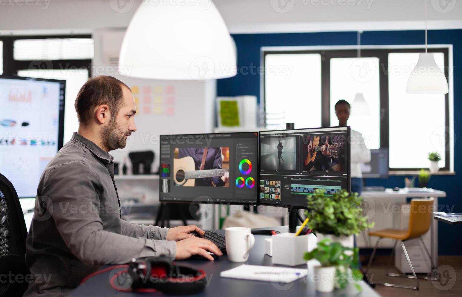 editor processing movie montage cutting footage and sound using post production software and two monitors. Man videographer editing film project in digital multimedia star up company photo