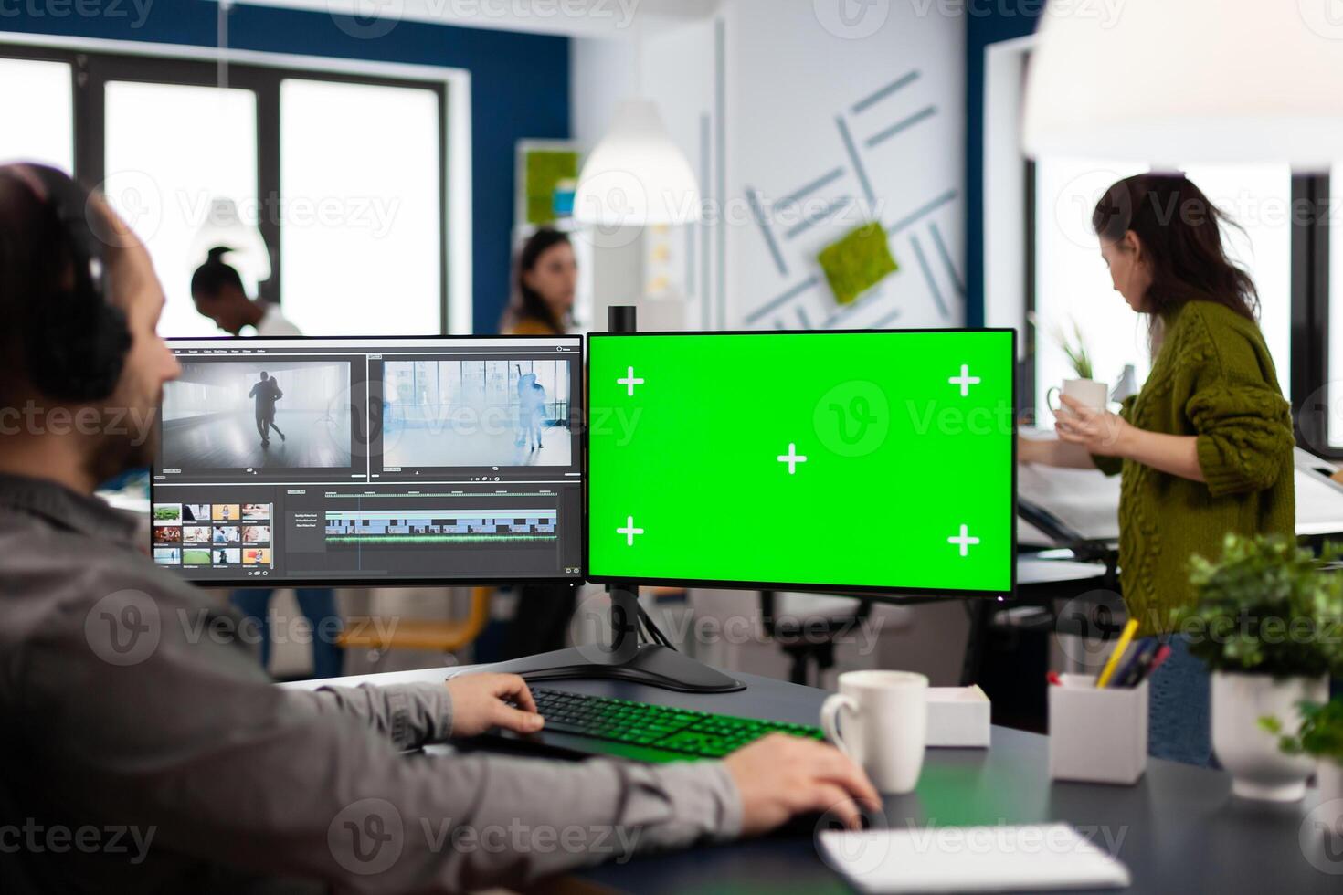 Videographer using computer with chroma key, mock up isolated display editing and audio footage. Man editor processing film montage on pc with green screen while team working in background photo