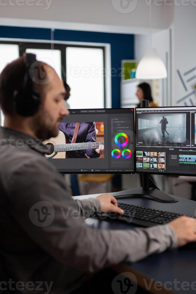 Graphic production working on pc with two displays editing and audio footage sitting in creative workplace. maker employee processing film montage in digital multimedia company photo
