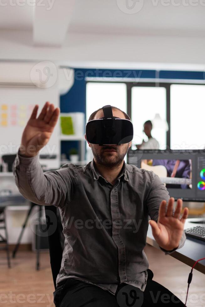 Professional man videographer making gestures with augmented reality headset, prosessing film montage in post production program. editor using high tech office VR modeling software application photo