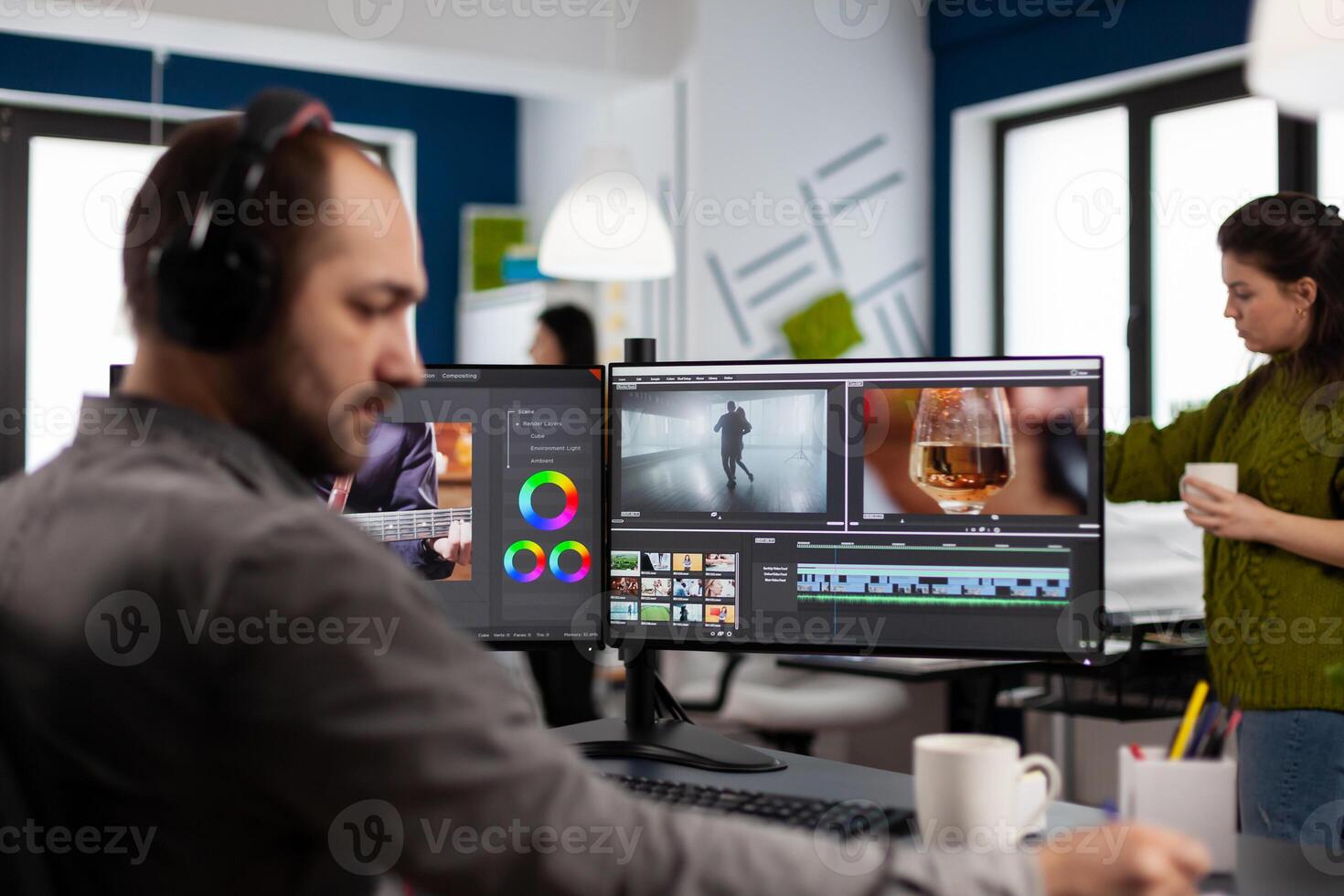 Videographer with headset working with footage and sound on pc with two displays, taking notes while editing customer . Man processing film montage sitting in creative startup agency office. photo