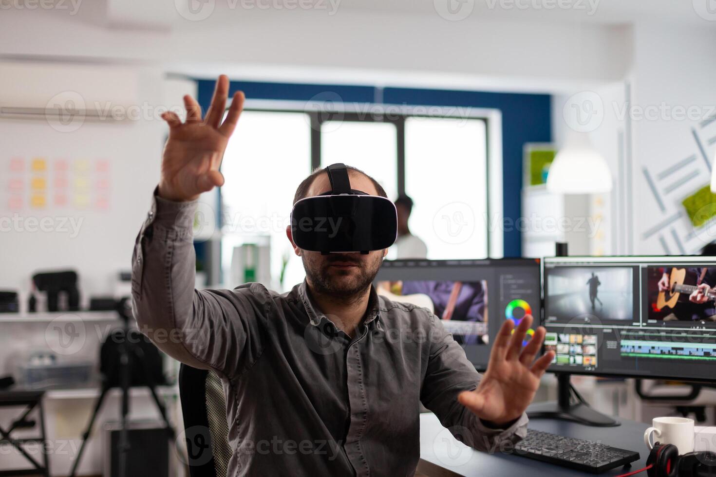editor experiencing virtual reality headset, gesturing, editing film montage using post production software working in creative agency office. Videographer using VR goggles in multimedia company photo