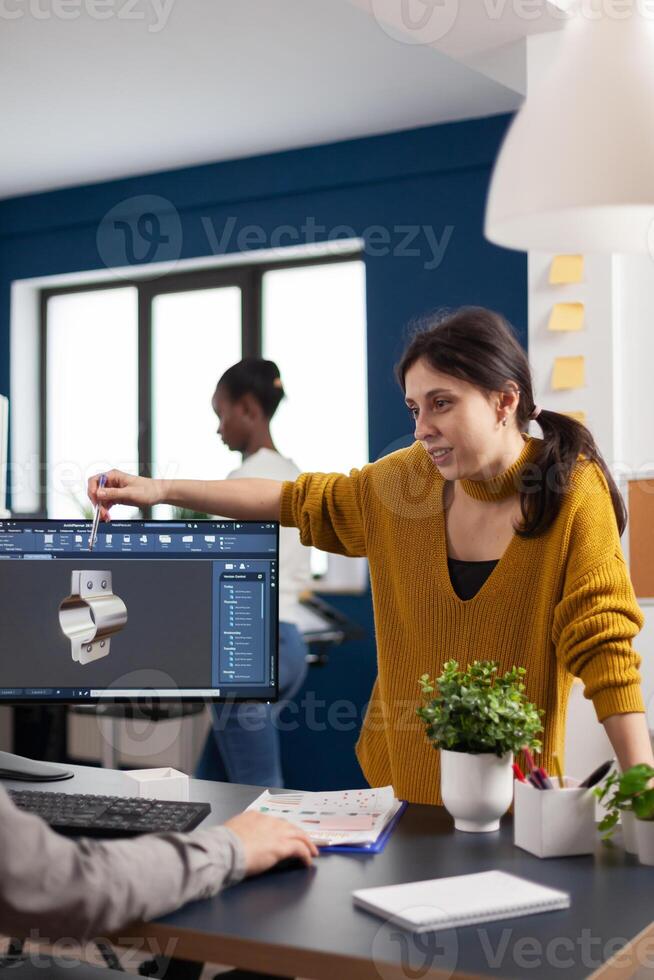 Team discussing about industrial project using dual monitors setup to desing 3D gears and metalic clamp in CAD software. Woman industrial engineer project manager working in creative office photo