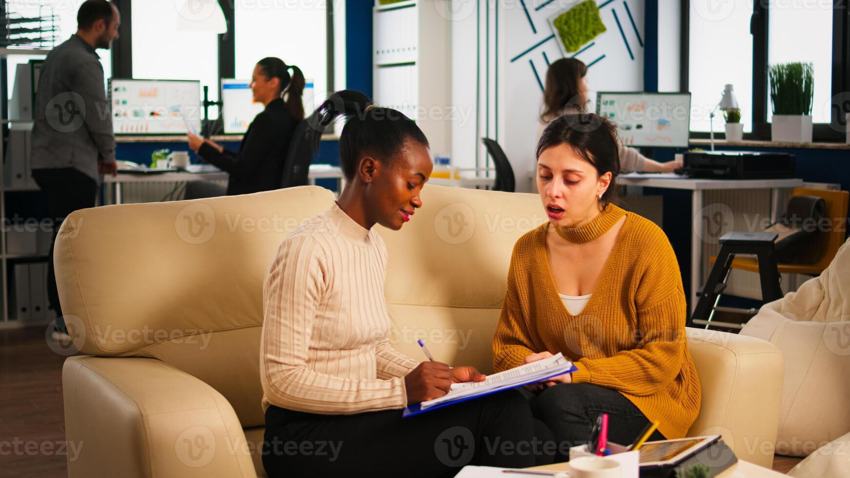 Young diverse woman holding paper document, discussing contract with confident partner in casual wear, signing investment papers. Businesswomen shaking hands, making satisfactorily agreement. photo