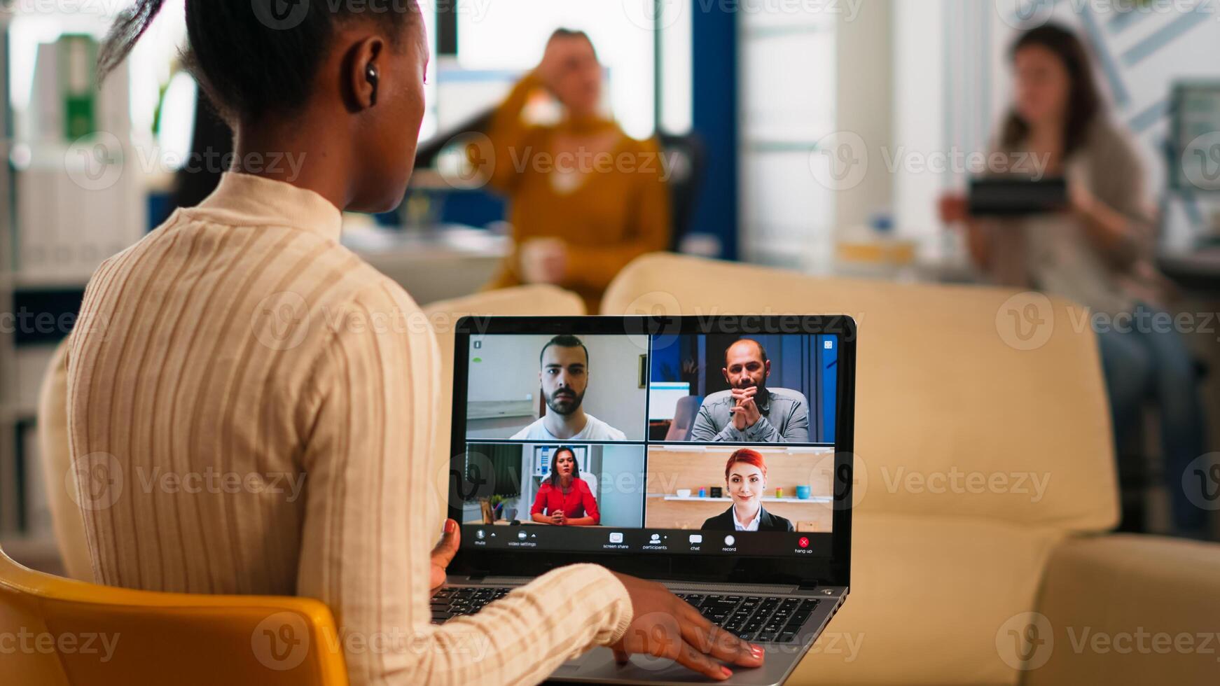 Over the sholder shot of employee talking with partners using call holding laptop sitting on couch in business modern office. Diverse coworkers planning new financial project in modern company photo