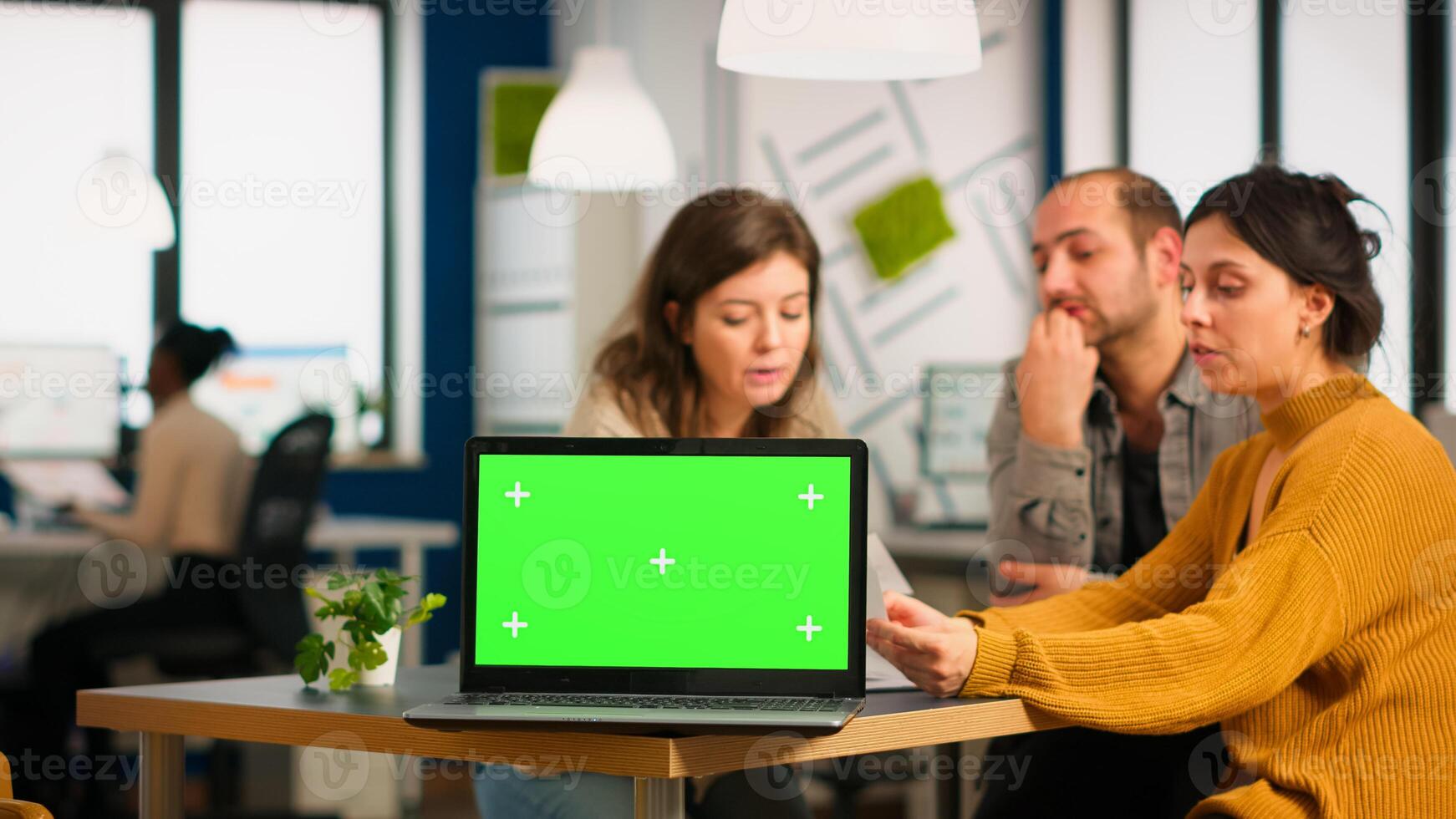 Group of business people discussing company plan with mockup laptop in front of camera, pc ready for financial project presentation placed on desk. Leader using green screen pc with chroma key display photo