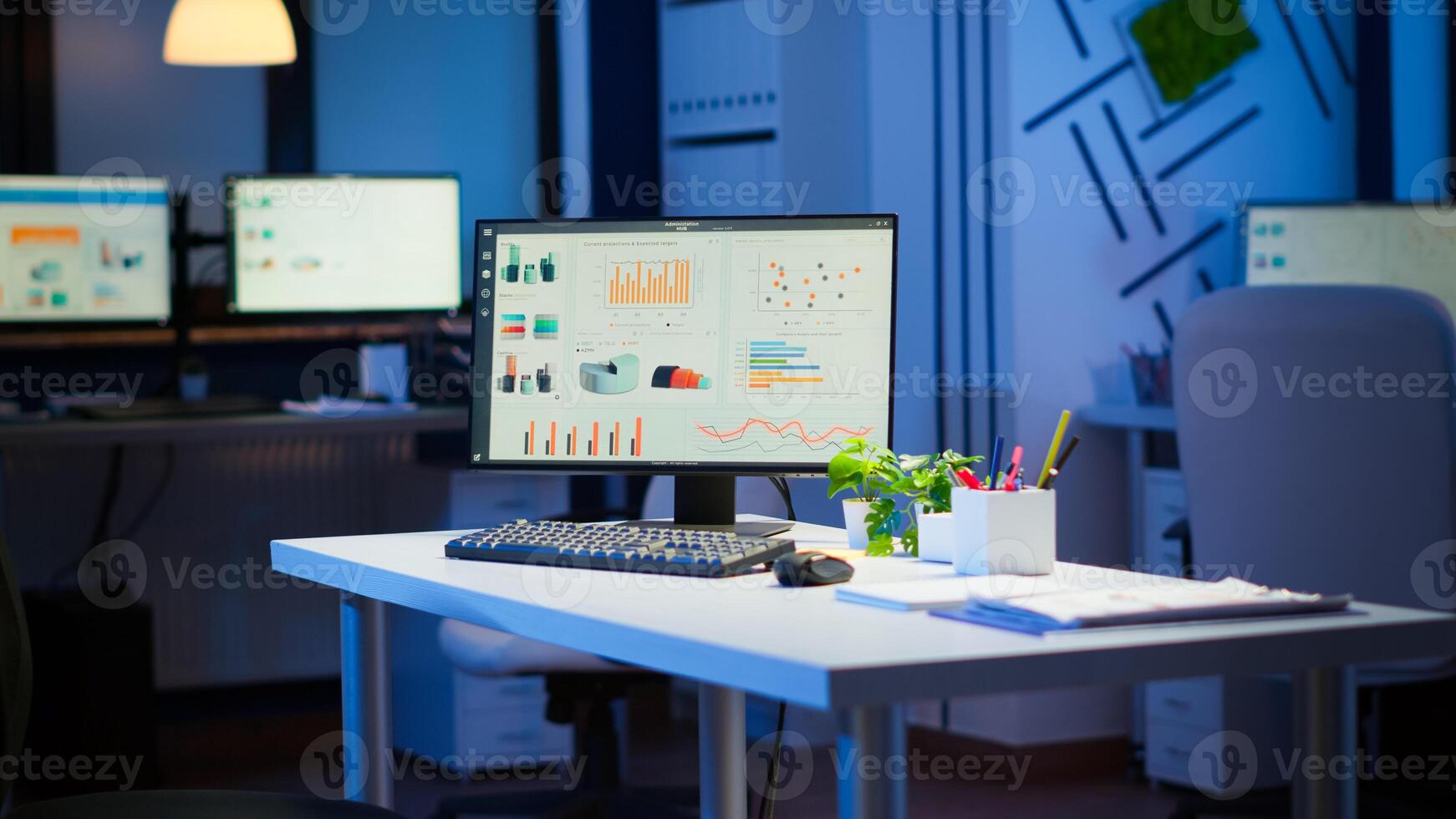 Empty start up business office with modern design during night with graphics running on the desktop. Financial company with nobody in it, place of work startup, workplace indoors concept photo