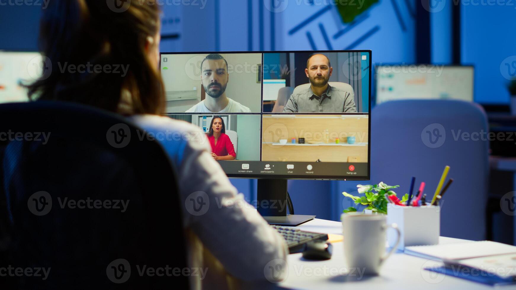 Back view of business woman talking about sale report in conference working overtime in start-up office. Team using online wireless communication discussing on webcam during group meeting. photo
