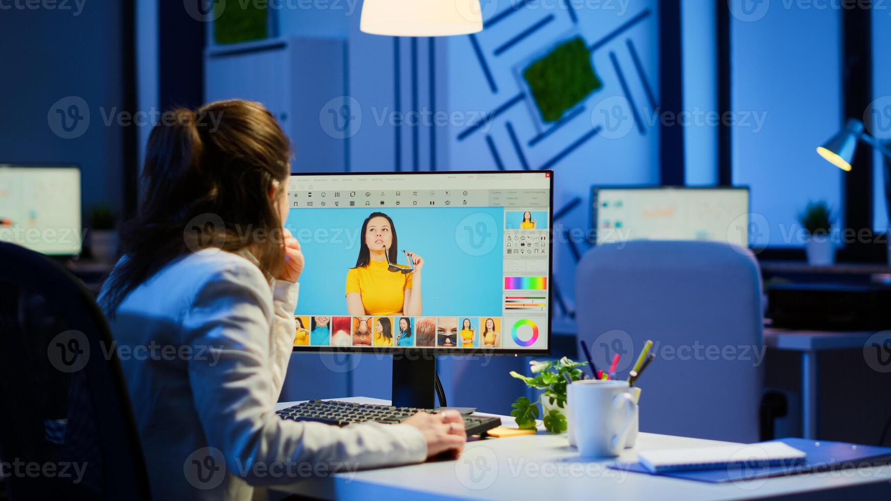 Freelancer retoucher woman working overtime on laptop computer with photo editing software. Professional graphic editor retouching photos of a client during night time in home office on performance pc