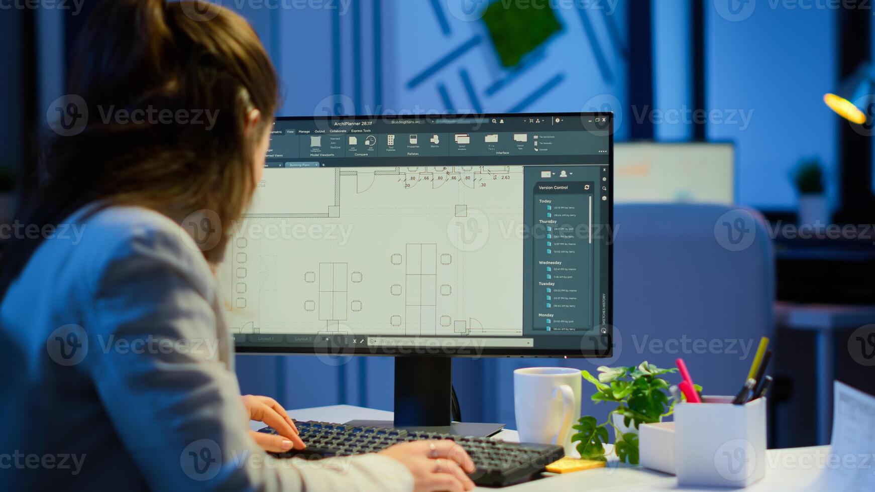 Over the shoulder shot of engineer working with architectural plans, cad software on desktop computer. Designer using arhitecture blueprints of buildings working overtime, creating and studying photo