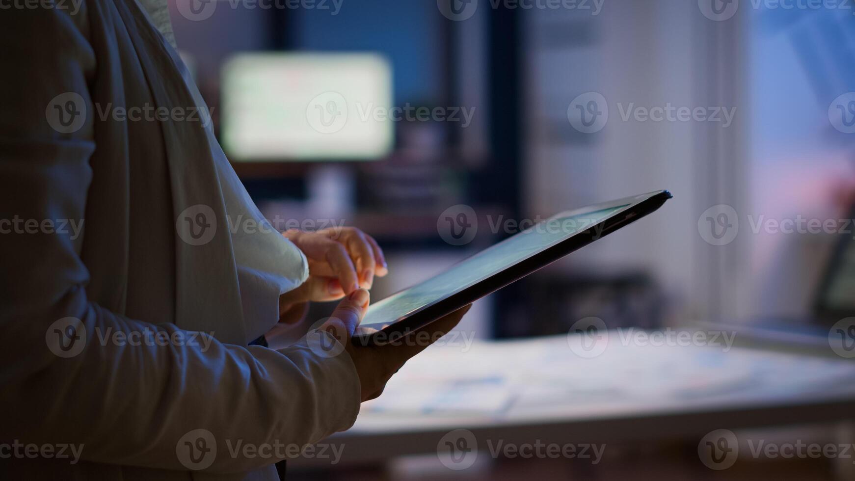 Close up of woman employee texting, sending and reading messages during break standing in business office late at night. Businesswoman using modern technology network wireless overworking in midnight photo