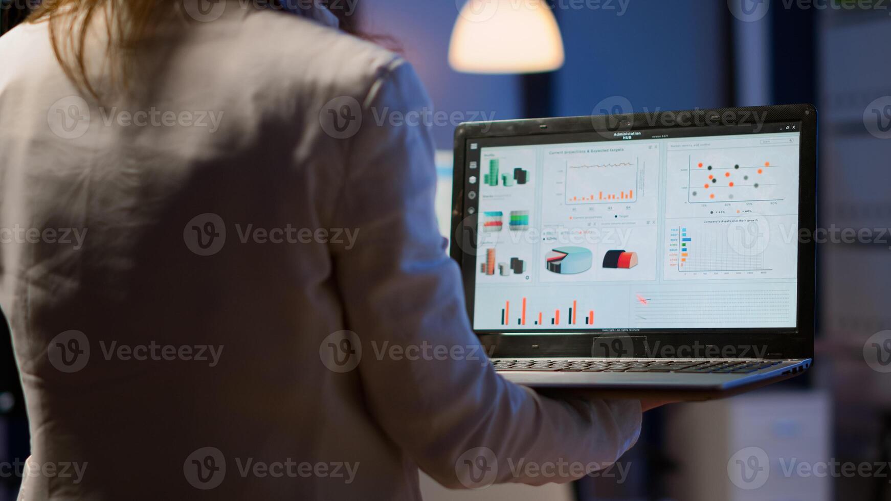 Close up of woman typing on laptop standing in start up business office late at night working. Busy focused employee using modern technology network wireless doing overtime for job searching, writting photo