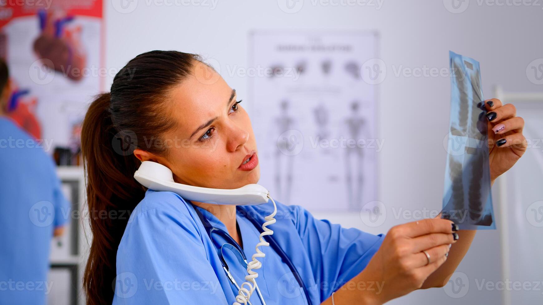Close up of assistant answering phone checking the result of patient x-ray and diagnosing him. Healthcare physician in medicine uniform, receptionist doctor nurse helping with telephone concultation photo