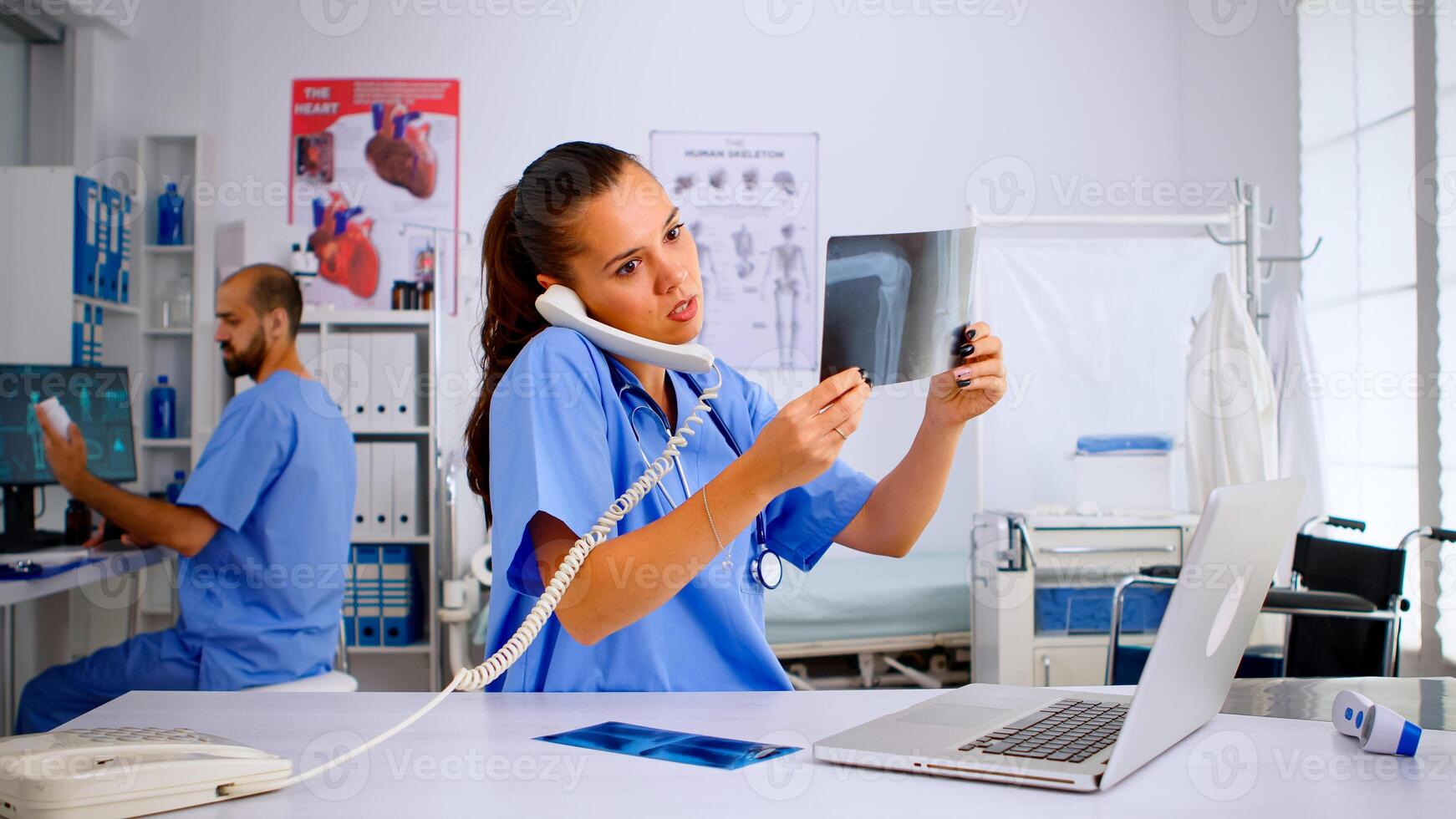 Nurse answering at hospital call checking the result of patient x-ray and diagnosing him. Healthcare physician in medicine uniform, receptionist doctor assistant helping with phone concultation photo