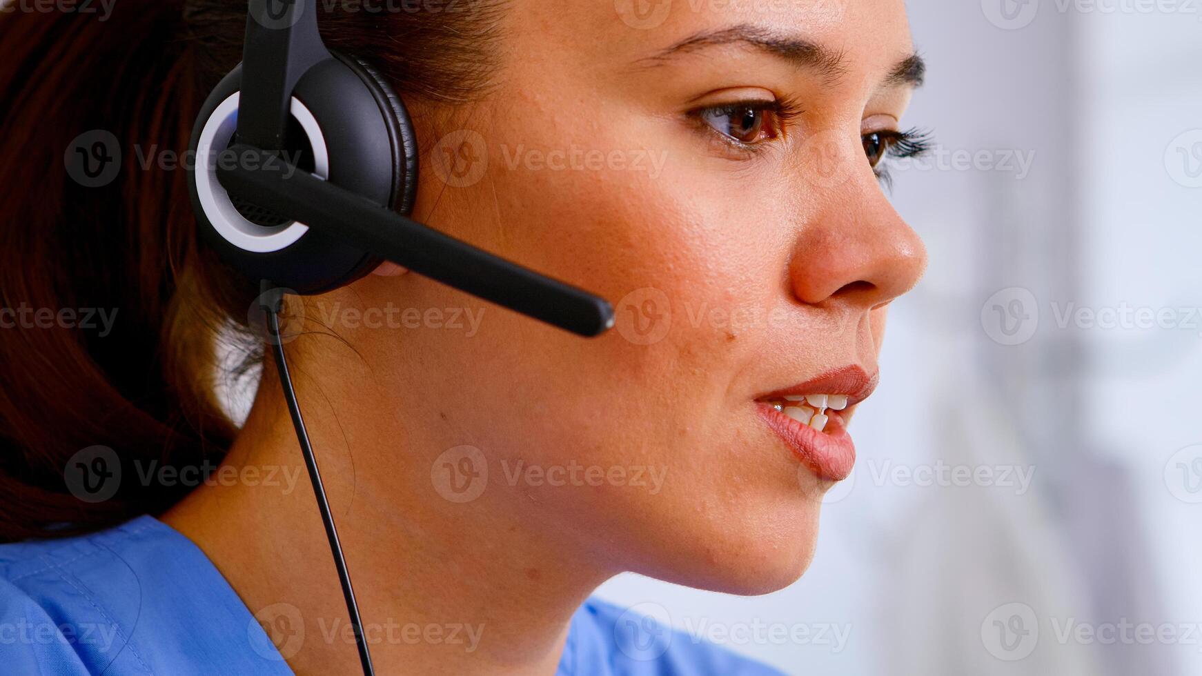 Close up of medical operator with headphone consulting patients during telehealth discussion in hospital. Healthcare physician in medicine uniform, doctor nurse assistent helping with appointment photo