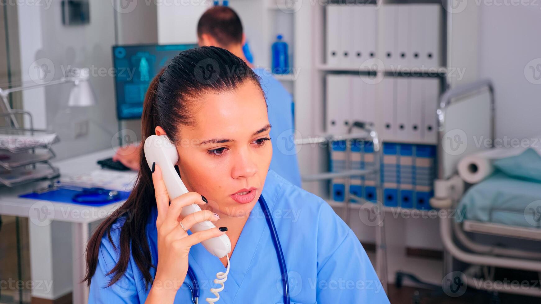 Healthcare physician answering telephone in hospital reception, telehealth, checking list of scheduled patients. Doctor assistant having a phone conversation with sick person during consultation. photo