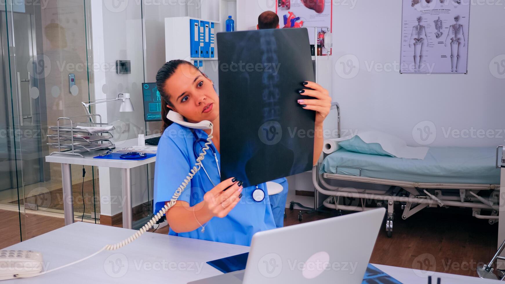 Nurse receptionist answering at hospital call checking the result of patient x-ray and diagnosing him. Healthcare physician in medicine uniform, doctor assistant helping with phone concultation photo