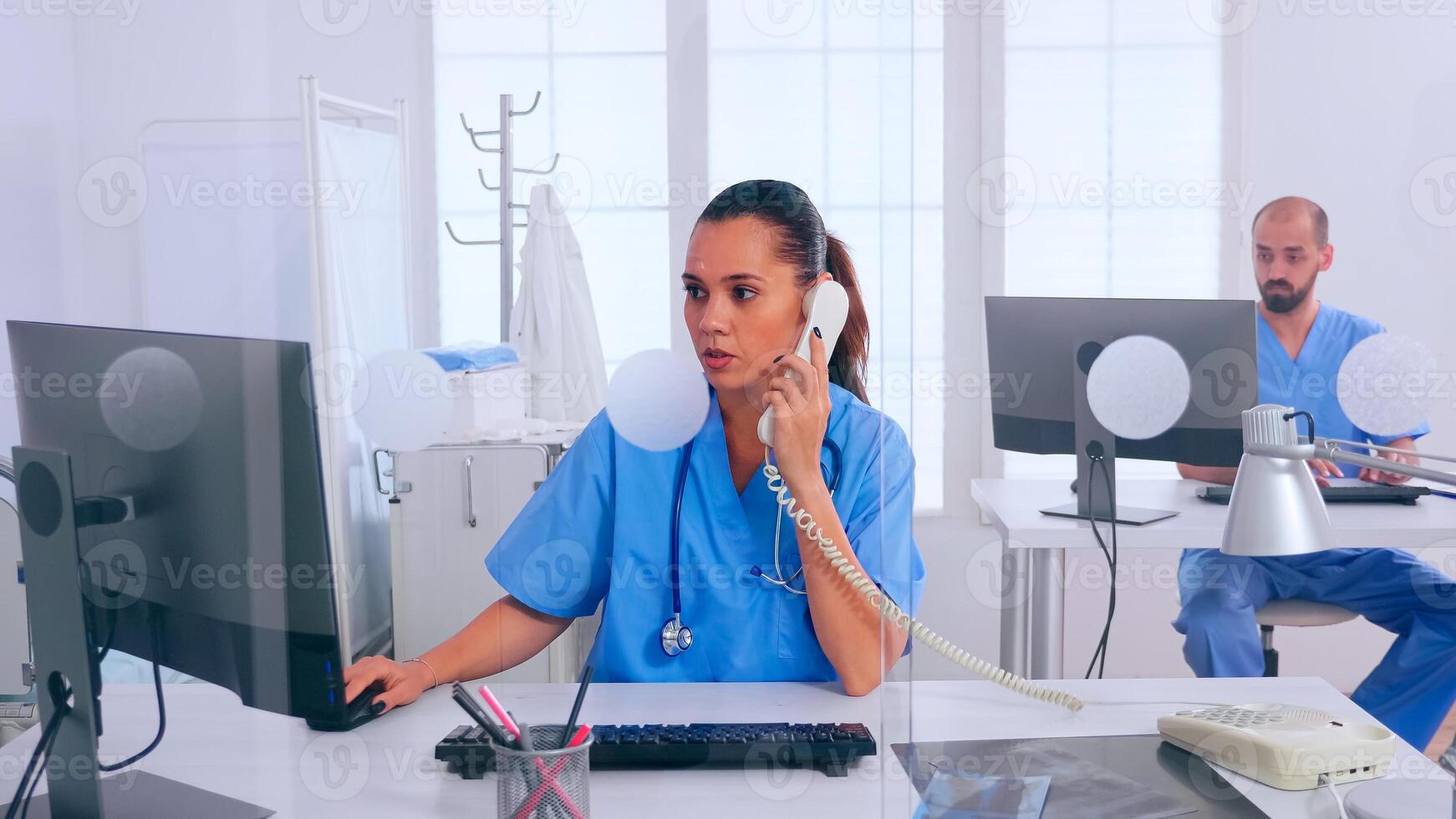 Woman receptionist answering at phone, working in hospital clinic writing on computer, making appointments. Medical physician in uniform writing list of consulted, diagnosed patients, making research. photo