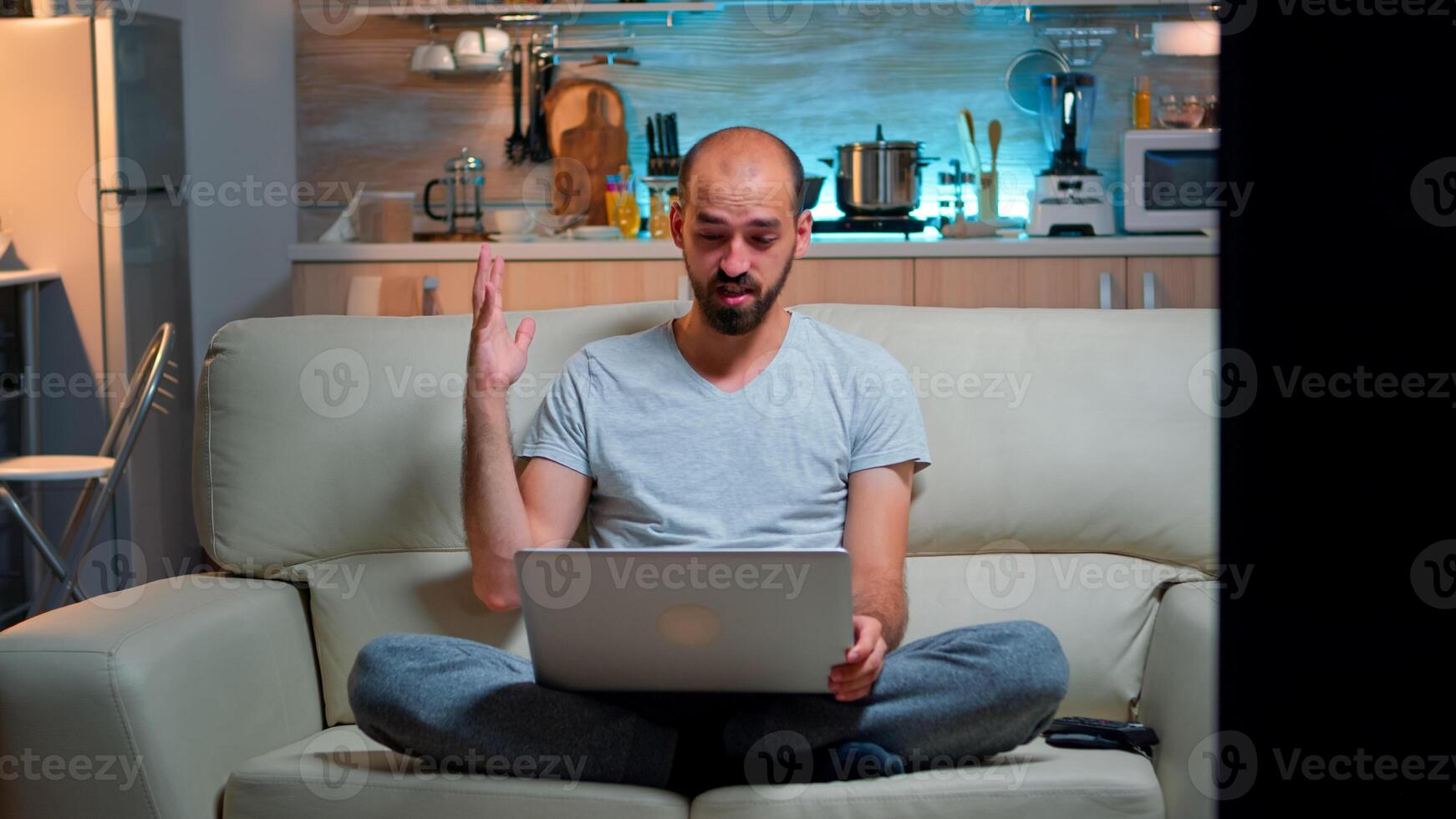 Focused man talking with business people during online meeting videocall on laptop computer. Caucasian person sitting on sofa late at night using videoconference online web internet communication photo