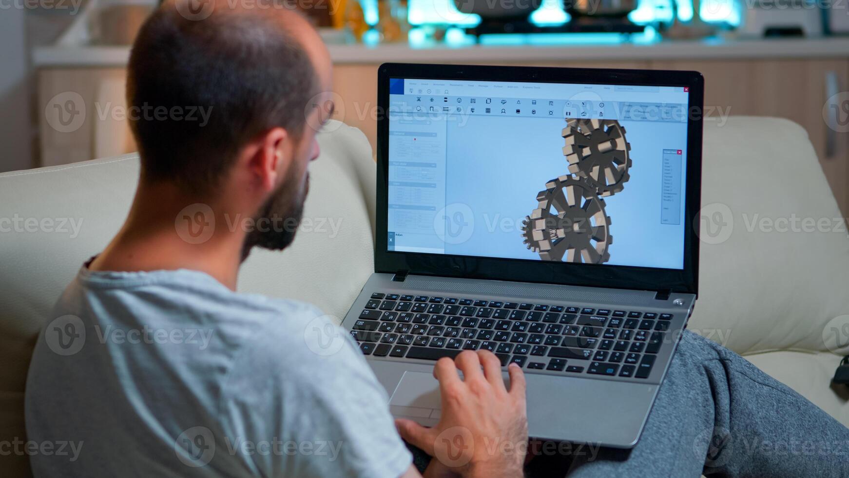 Focused architect looking at laptop computer for nerw development of technical construction prototype. Tired man working on digital design while sitting on couch working overtime from kitchen photo