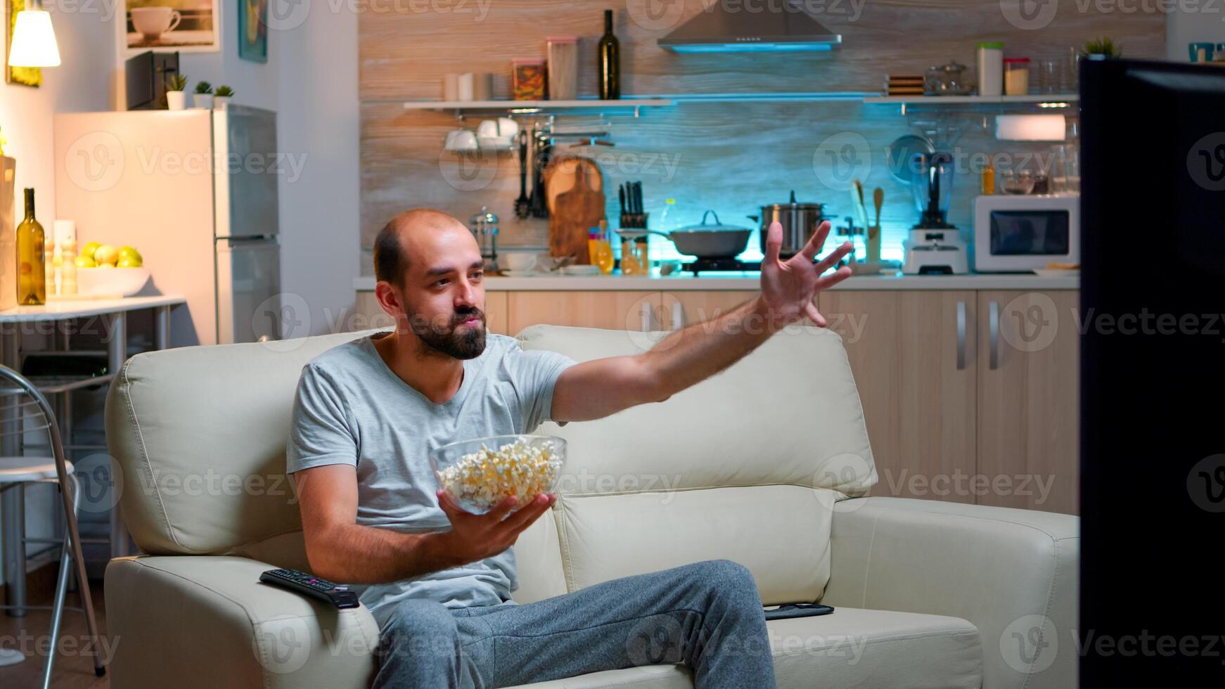 Caucasian football fan watching his team winning the competition, eating popcorn. Match goal in living room late at night, cheerful scoring win celebrating championship photo